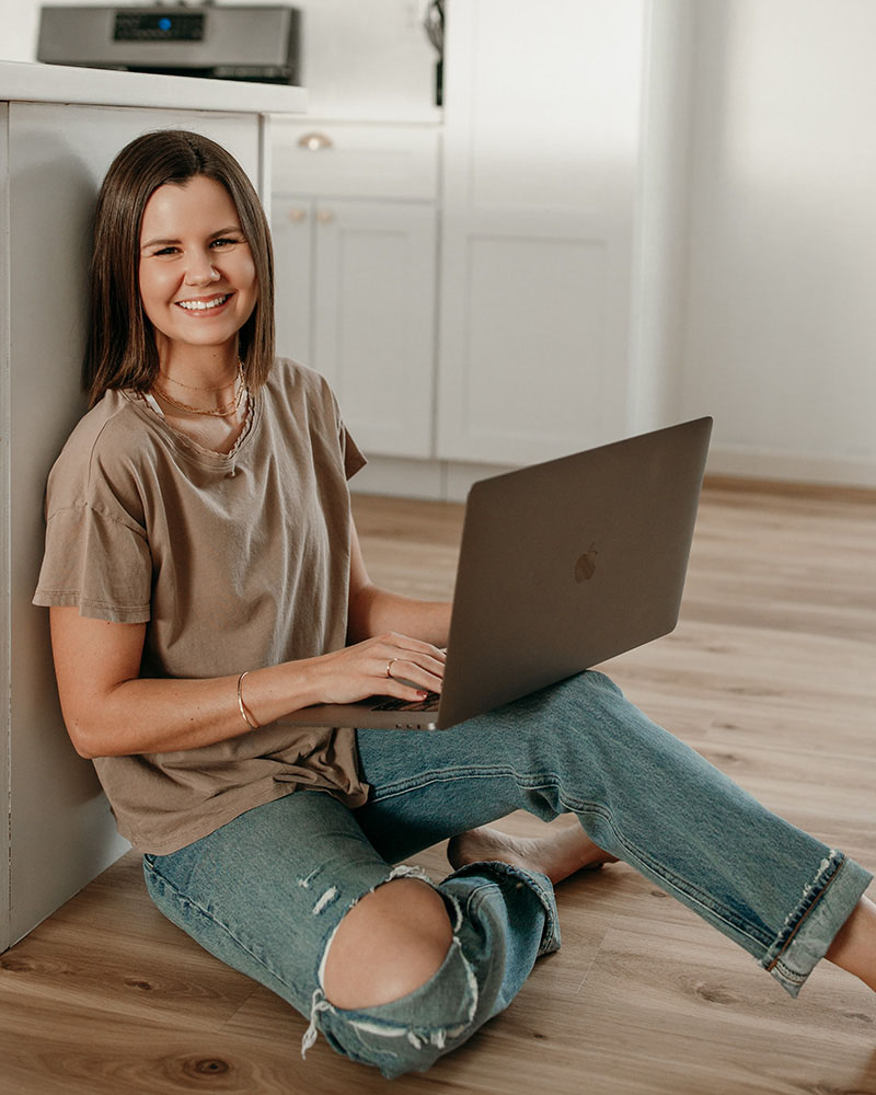 a woman sitting on the floor with a laptop